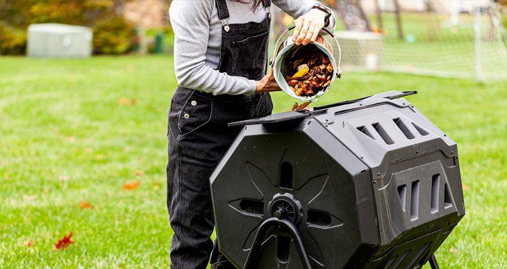 A man is pouring a bucket of compost into a composter.