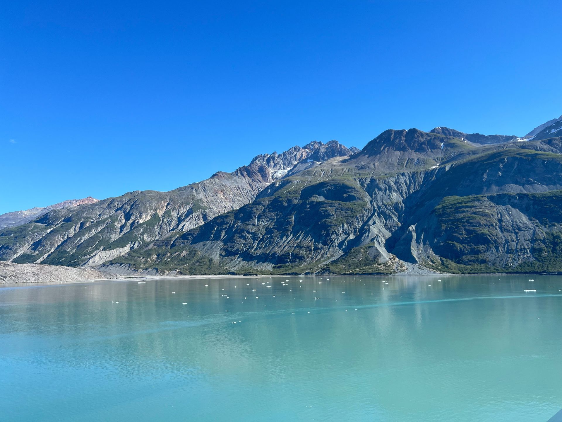 Blue water with mountains in background. Clear blue sky overhead.