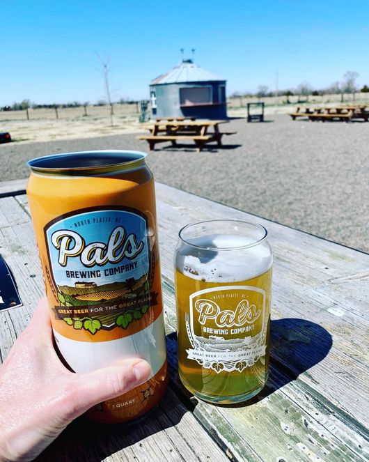 person holding a beer outside in the beer garden at pals brewing company in north platte