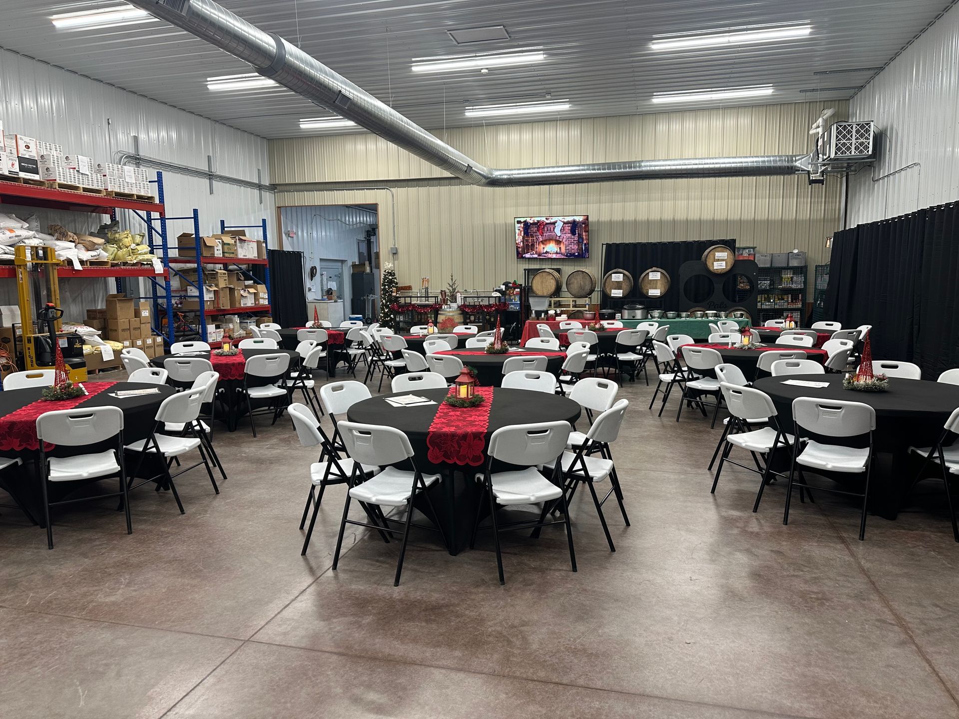 A building with a porch, blue sky with clouds. Tables and chairs are under the porch. Green grass and a sunny day.