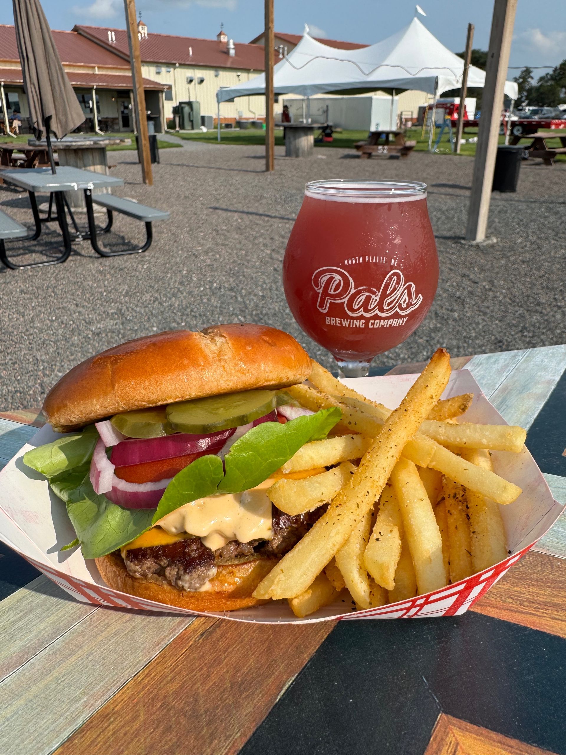 Close up of a Pals Smash Burger and seasoned fries in the outdoor beer oasis