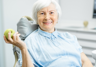 old woman with apple at dentist | Dental implants in S. Burlington VT 