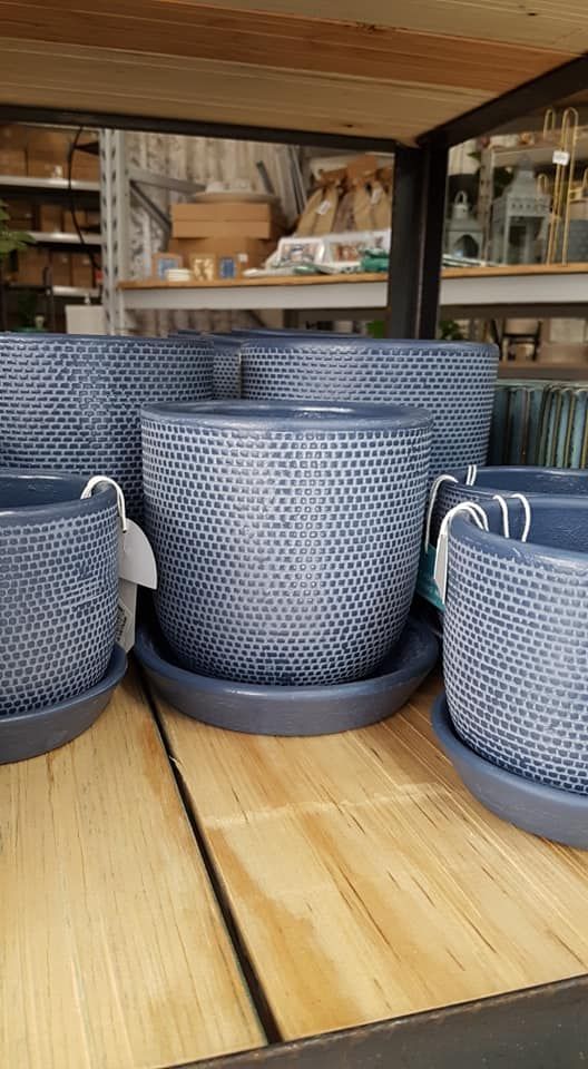 A row of blue pots and saucers sitting on top of a wooden table.