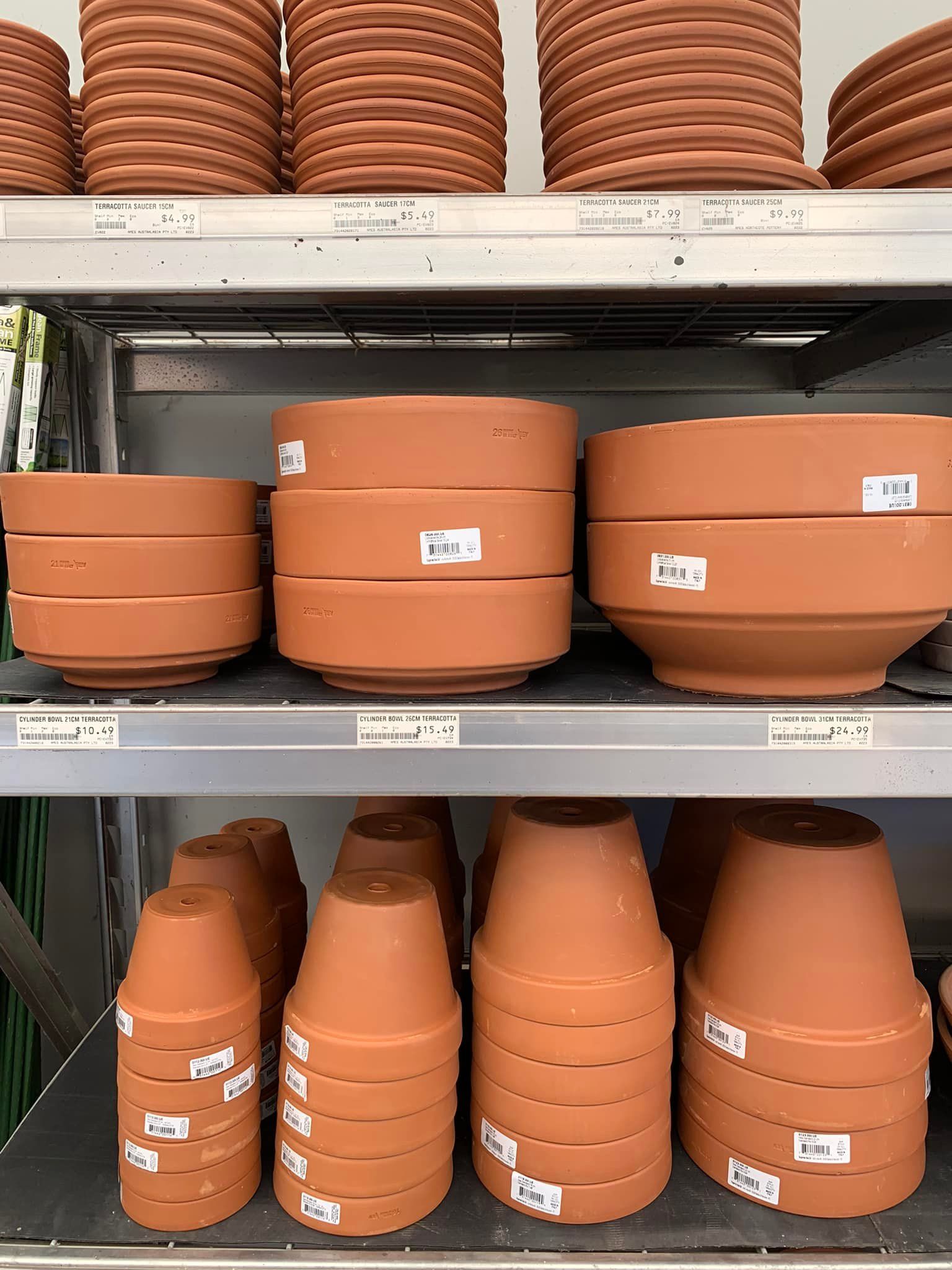 A shelf filled with lots of clay pots of different sizes.