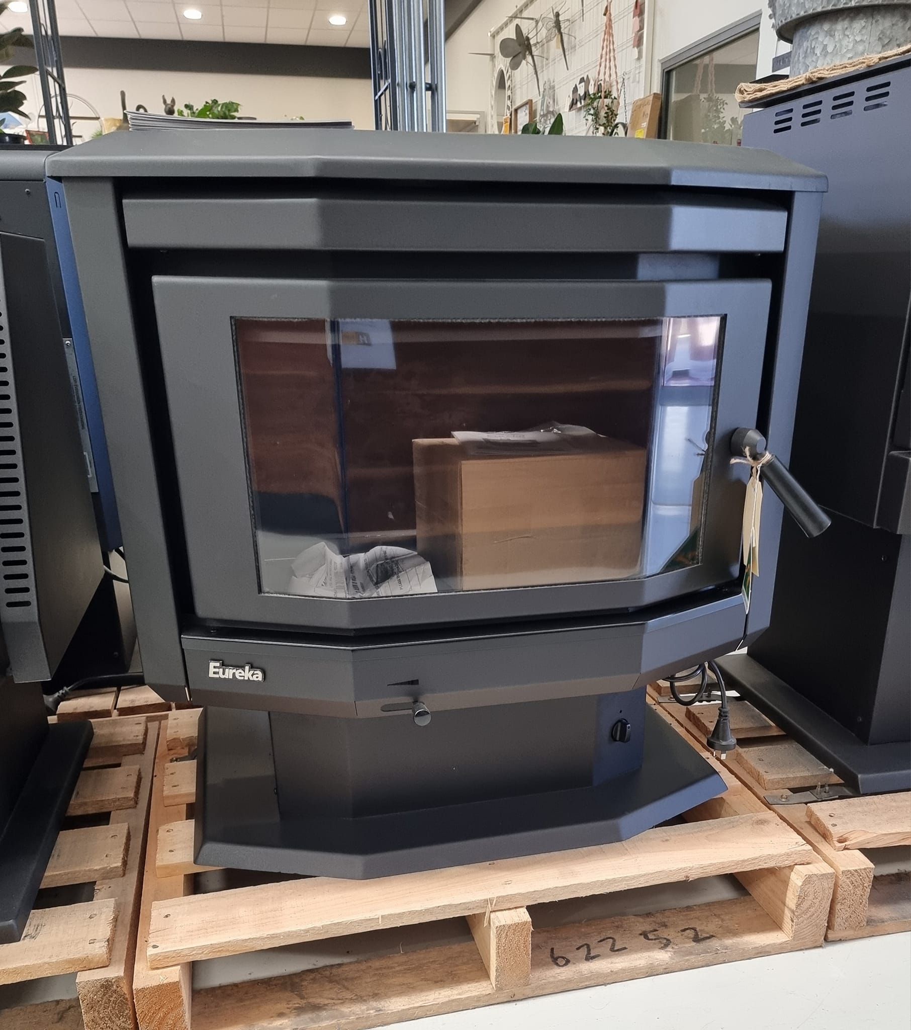 A black wood stove is sitting on top of a wooden pallet.