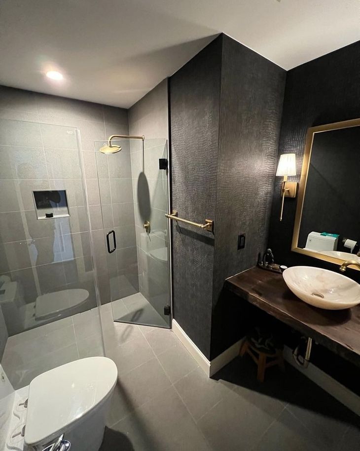 A bathroom with a toilet , sink , shower and mirror.