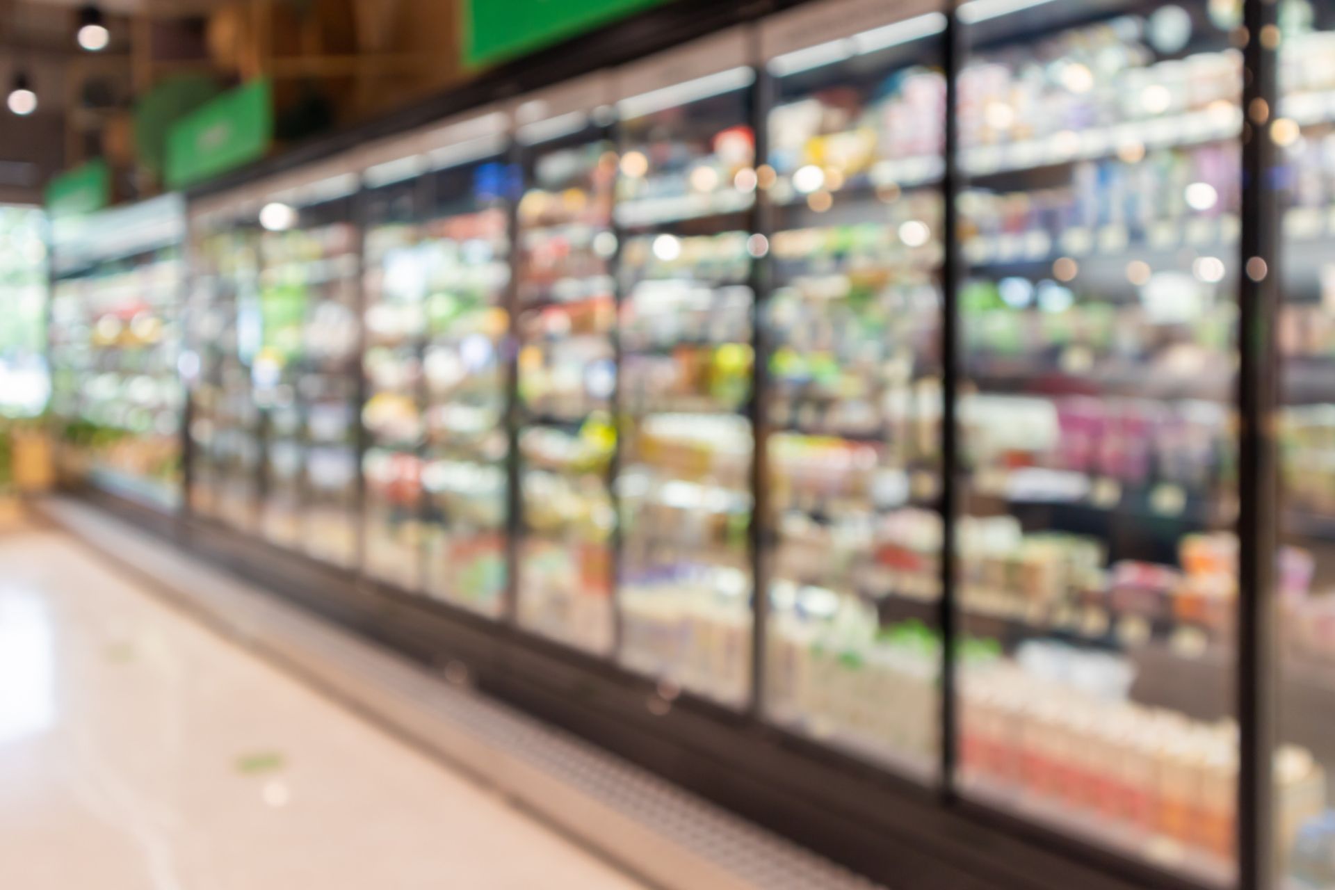 A blurred image of a grocery store with a row of refrigerators.