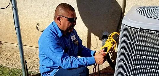A man is working on an air conditioner outside of a house.