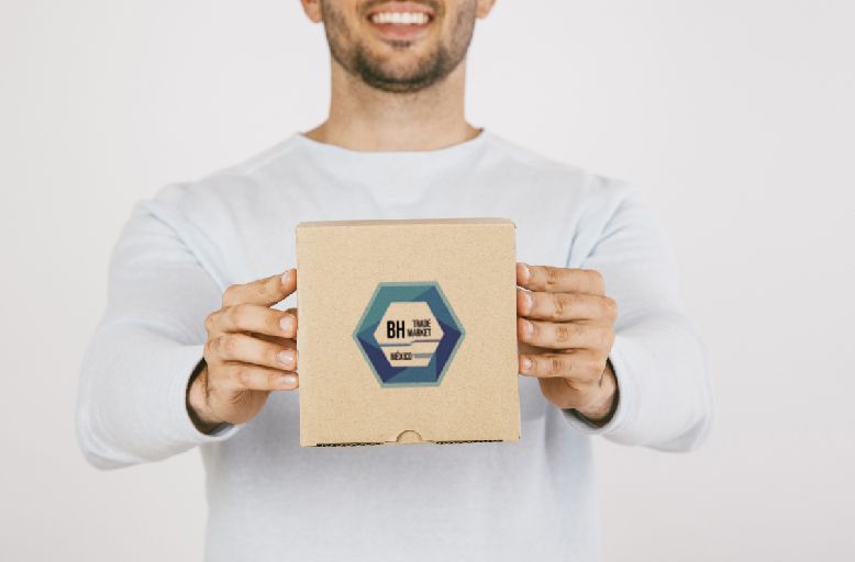 A man is holding a cardboard box with a blue logo on it.