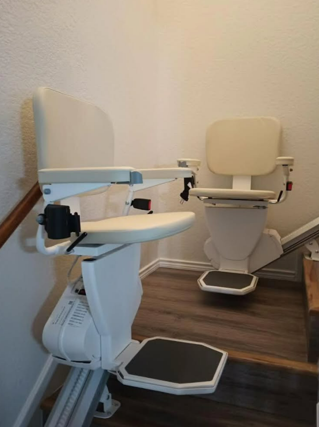 Two stairlifts, one in use and the other folded, along a staircase.
