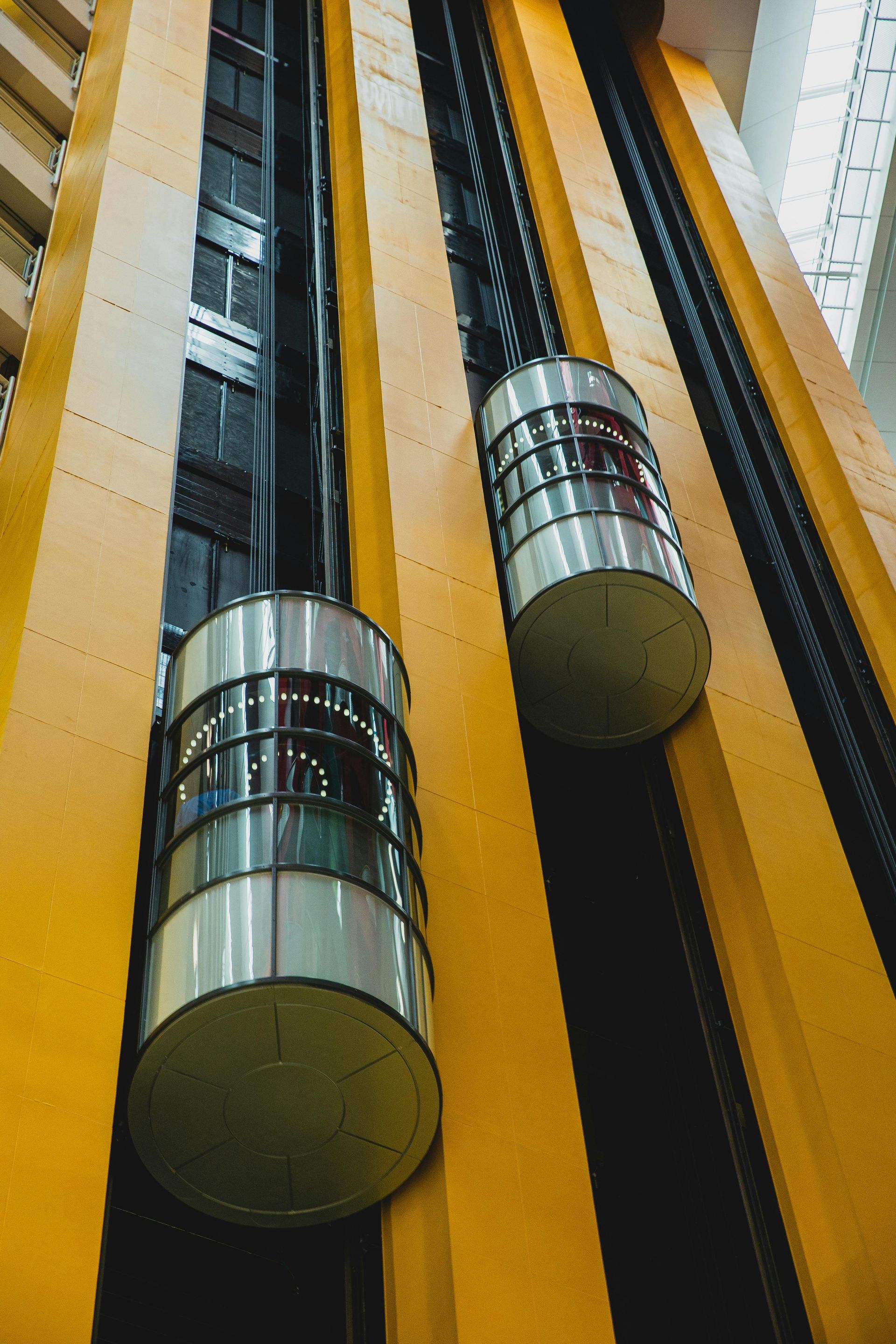 Two cylindrical elevators move up and down in a yellow shaft.