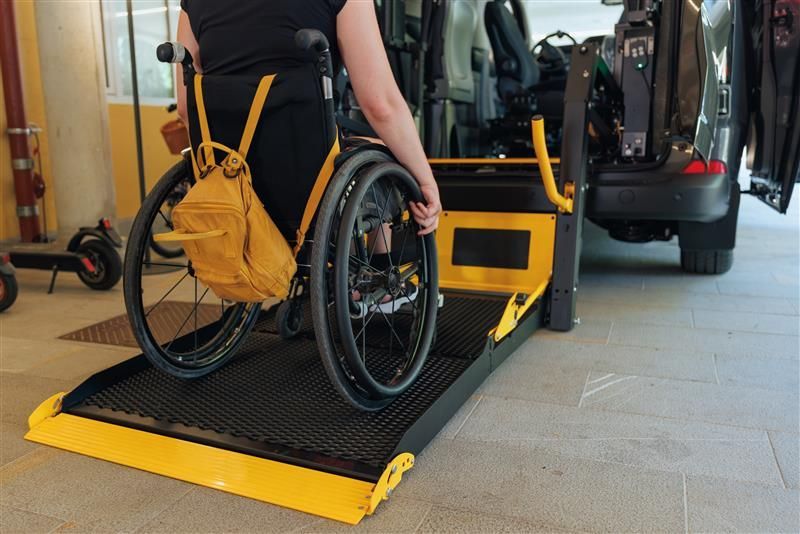 Person in a wheelchair using a yellow ramp to enter a vehicle.
