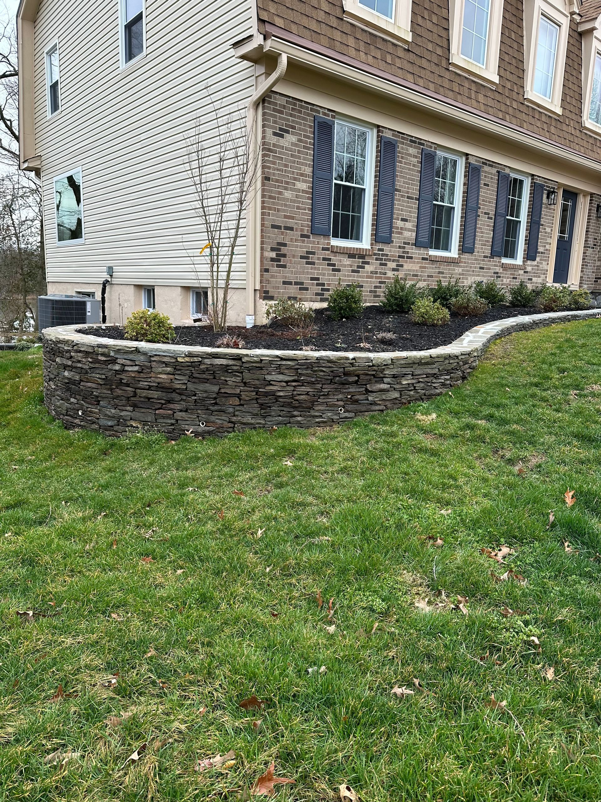 A large house with a stone wall in front of it.