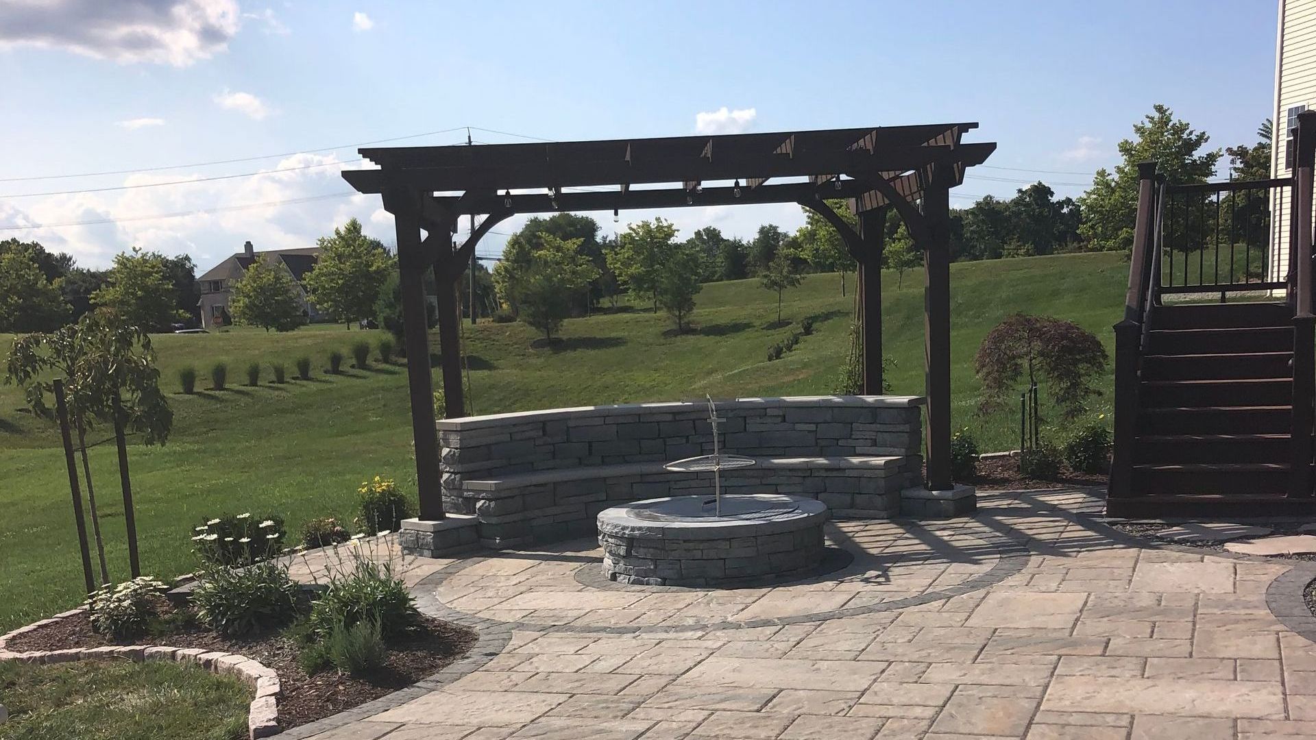A patio with a pergola and a fire pit