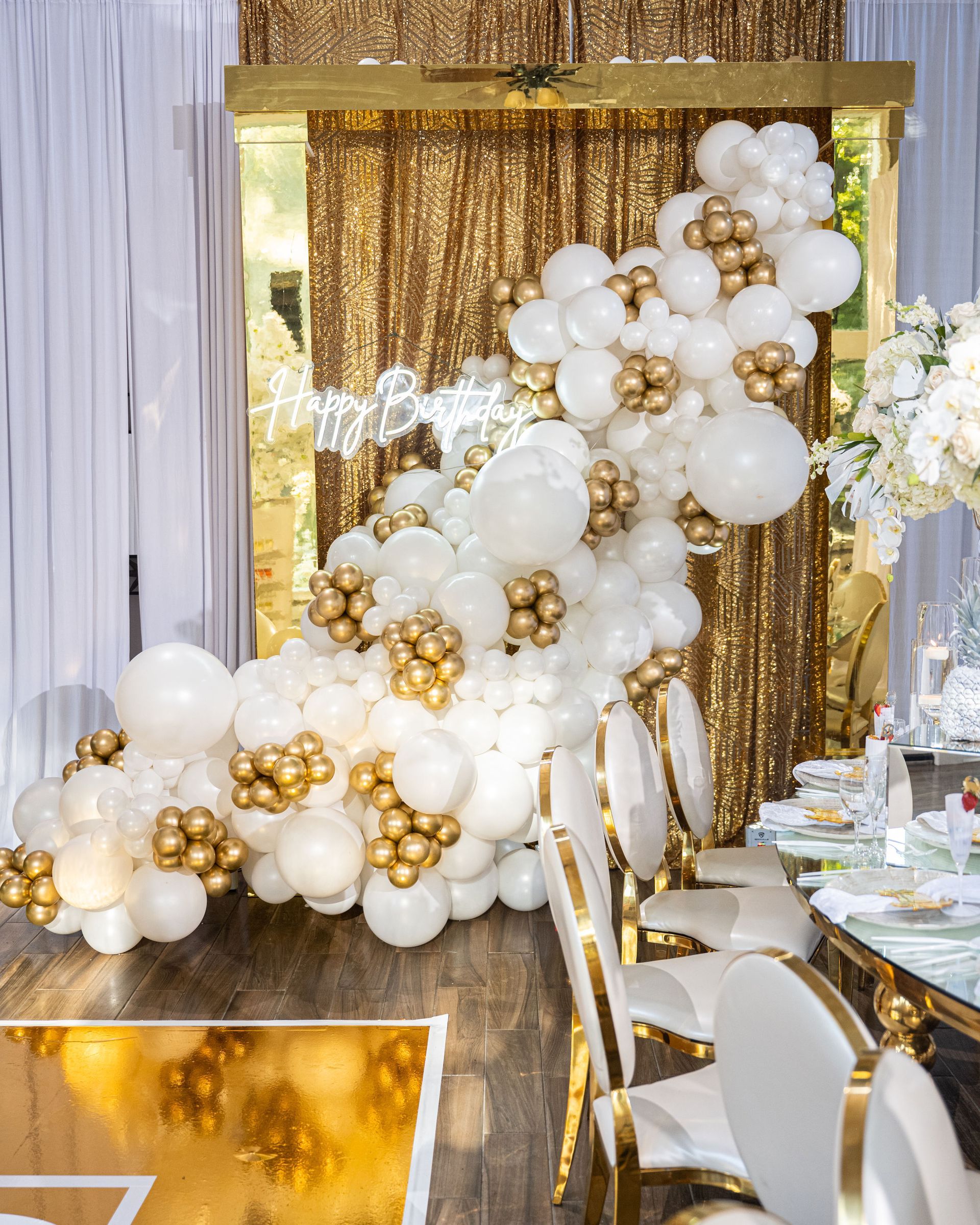 A room decorated with white and gold balloons for a birthday party.