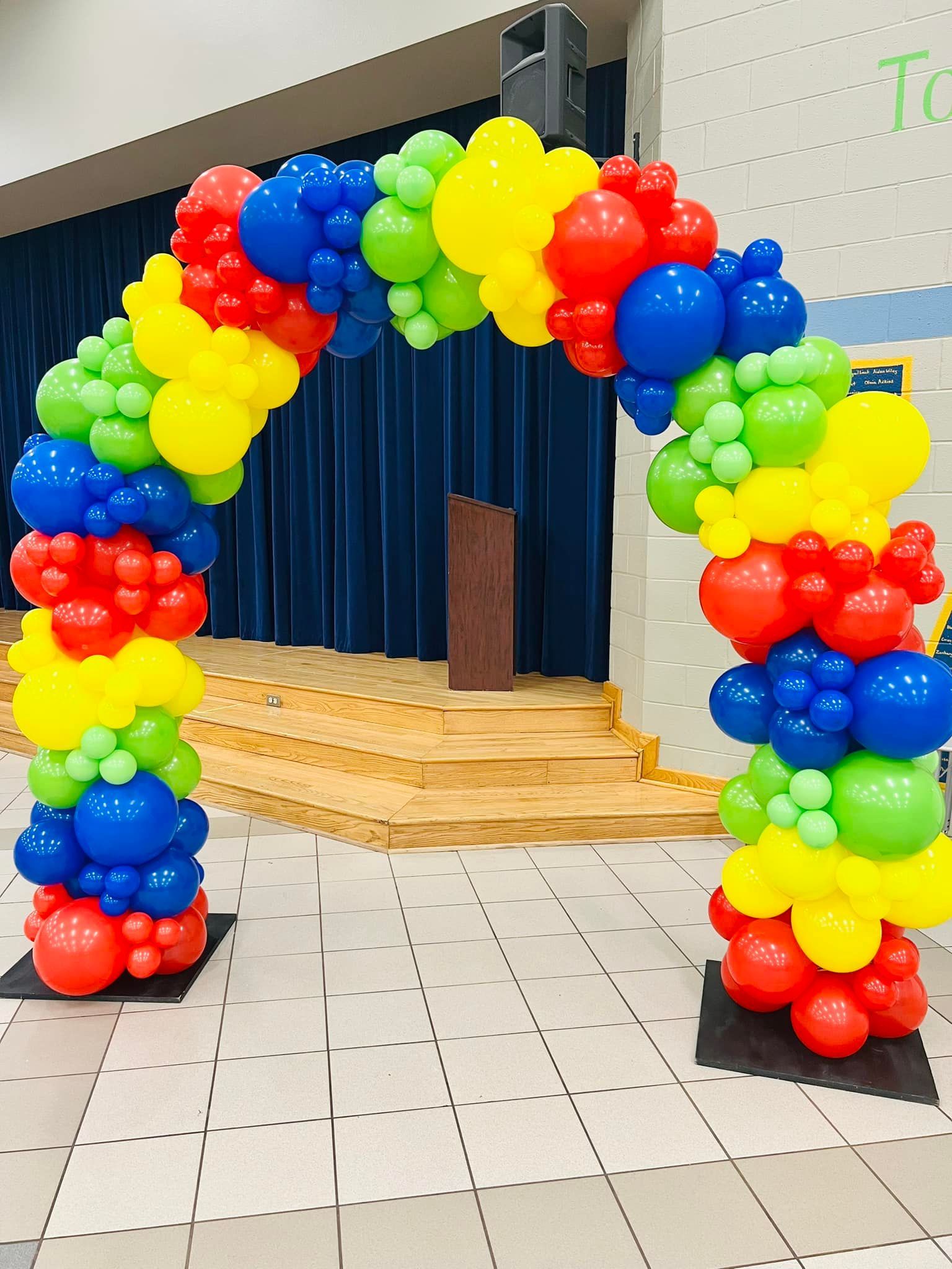 A colorful balloon arch is sitting in front of a stage.