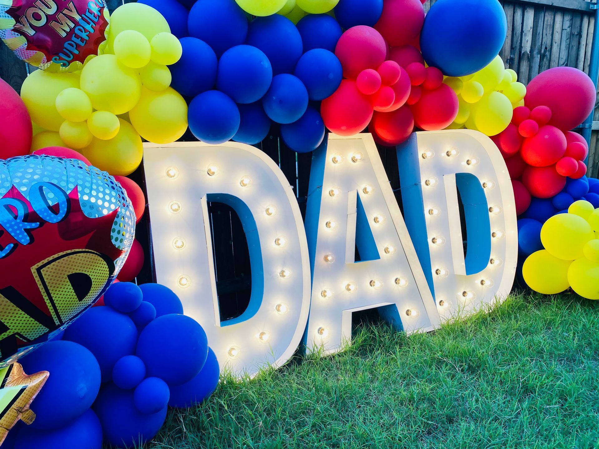 A sign that says dad is surrounded by balloons.
