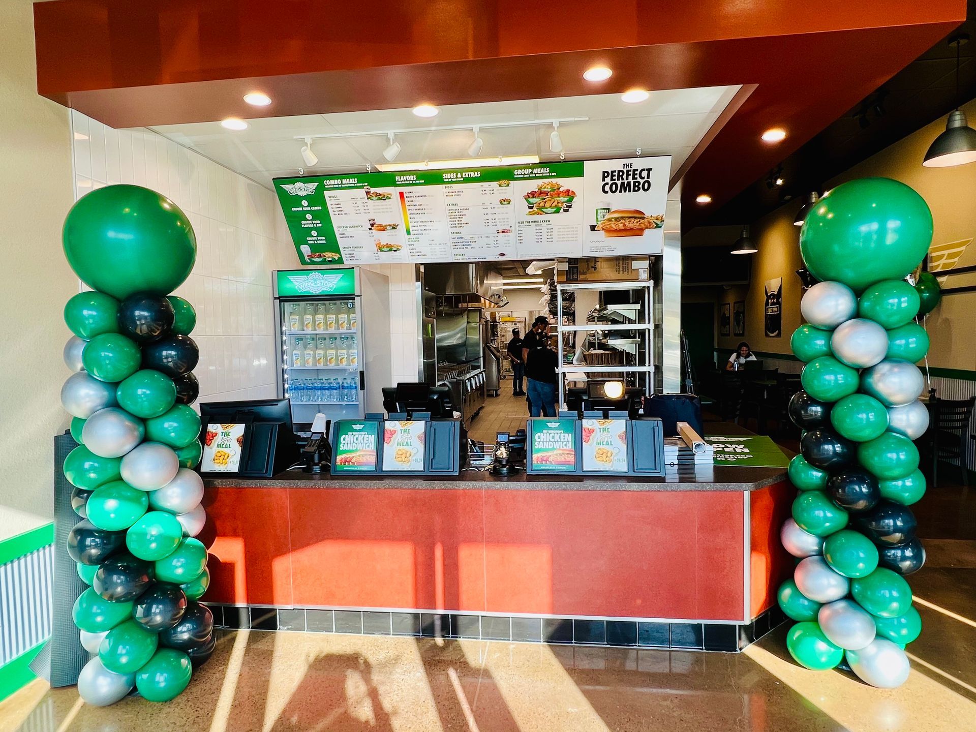 A restaurant with balloons on the columns in front of the counter.