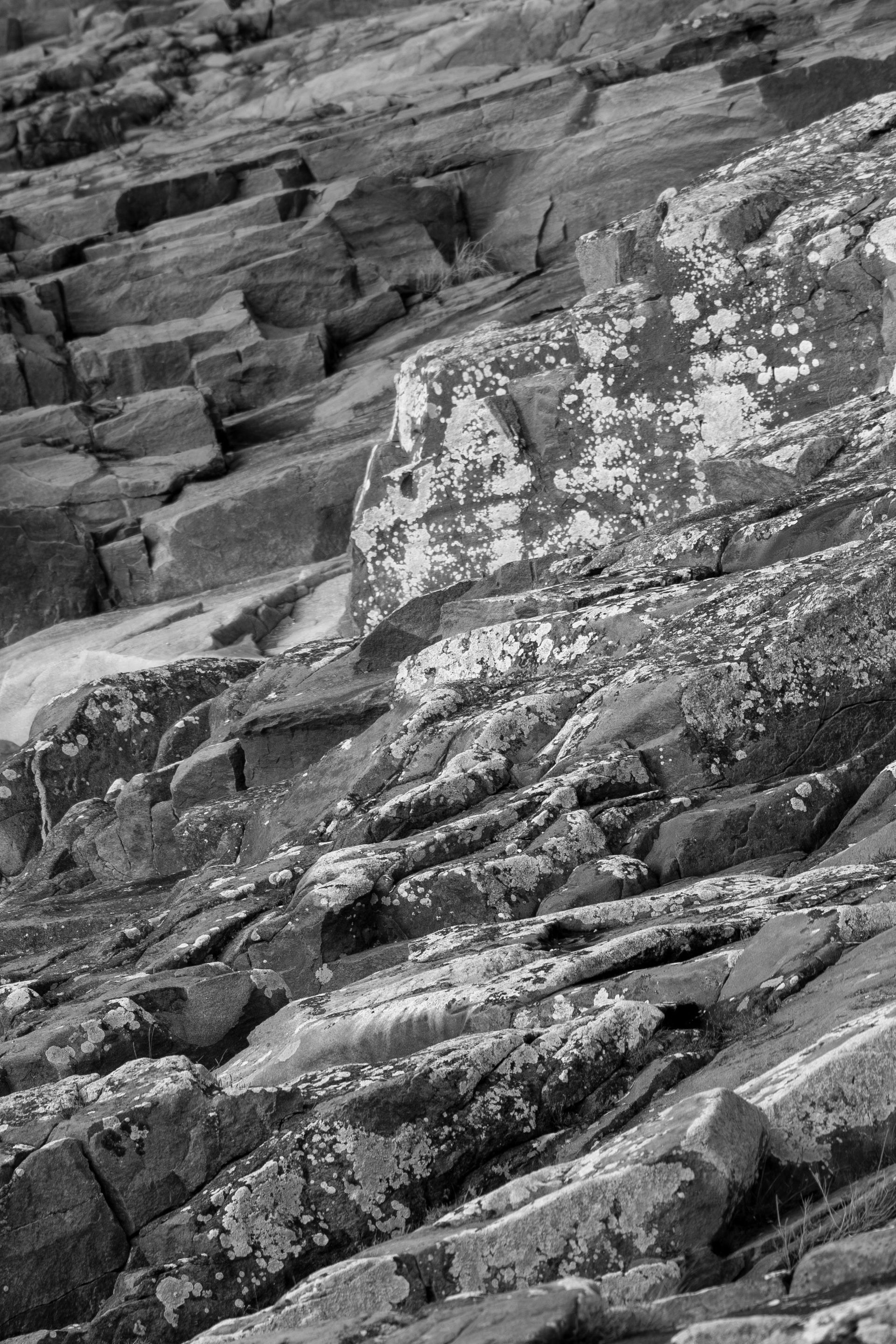 Ladera rocosa, texturizada con capas de piedra, en blanco y negro.