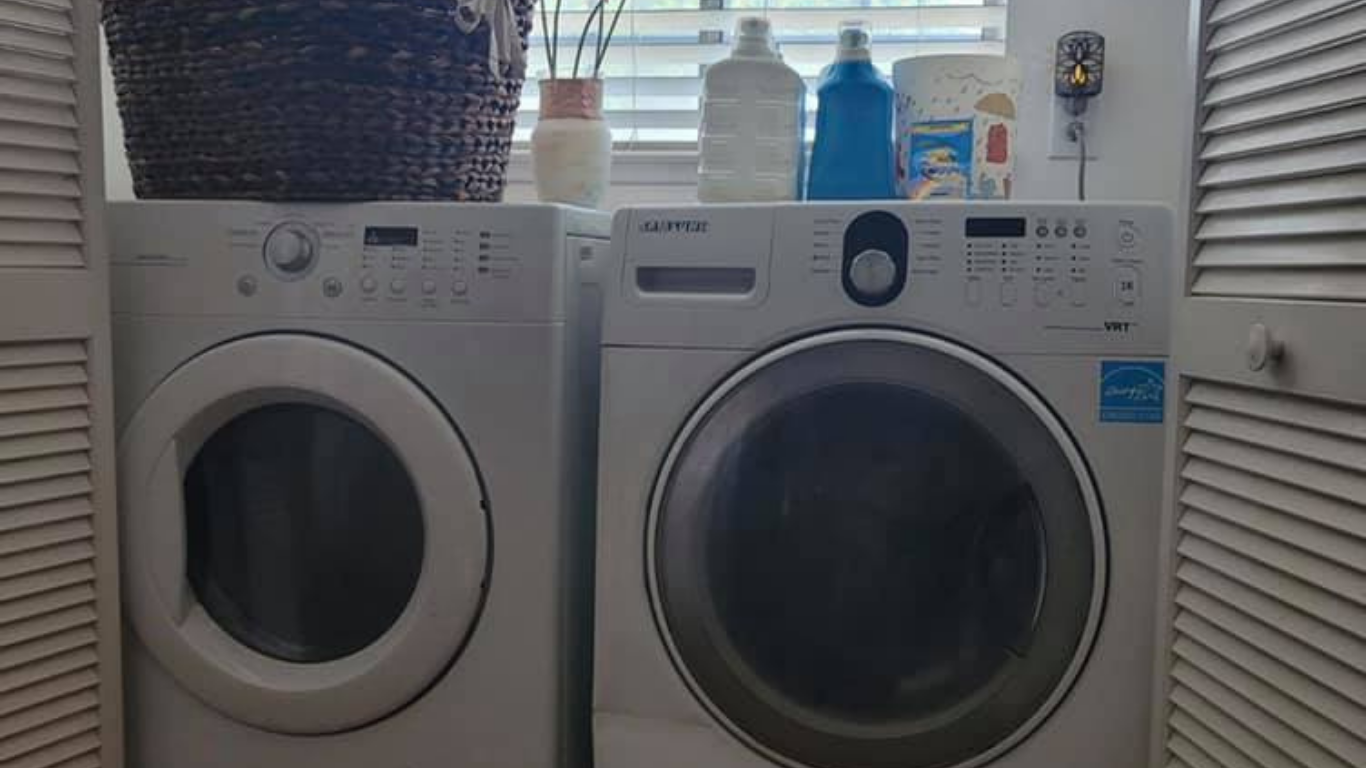 A front-loading washer and dryer in a laundry closet with a woven basket and cleaning supplies on top.