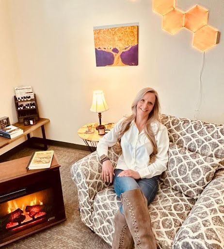 A woman is sitting on a couch in a living room next to a fireplace.