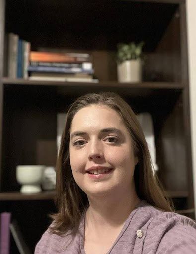 A woman is taking a selfie in front of a bookshelf.