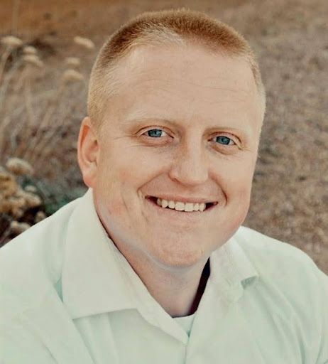 A man in a white shirt is smiling for the camera.