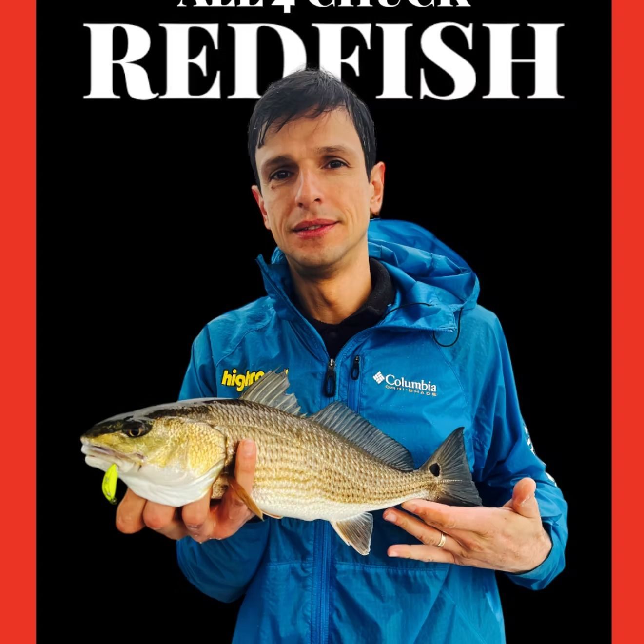 Man in blue jacket holding a redfish against a black background.