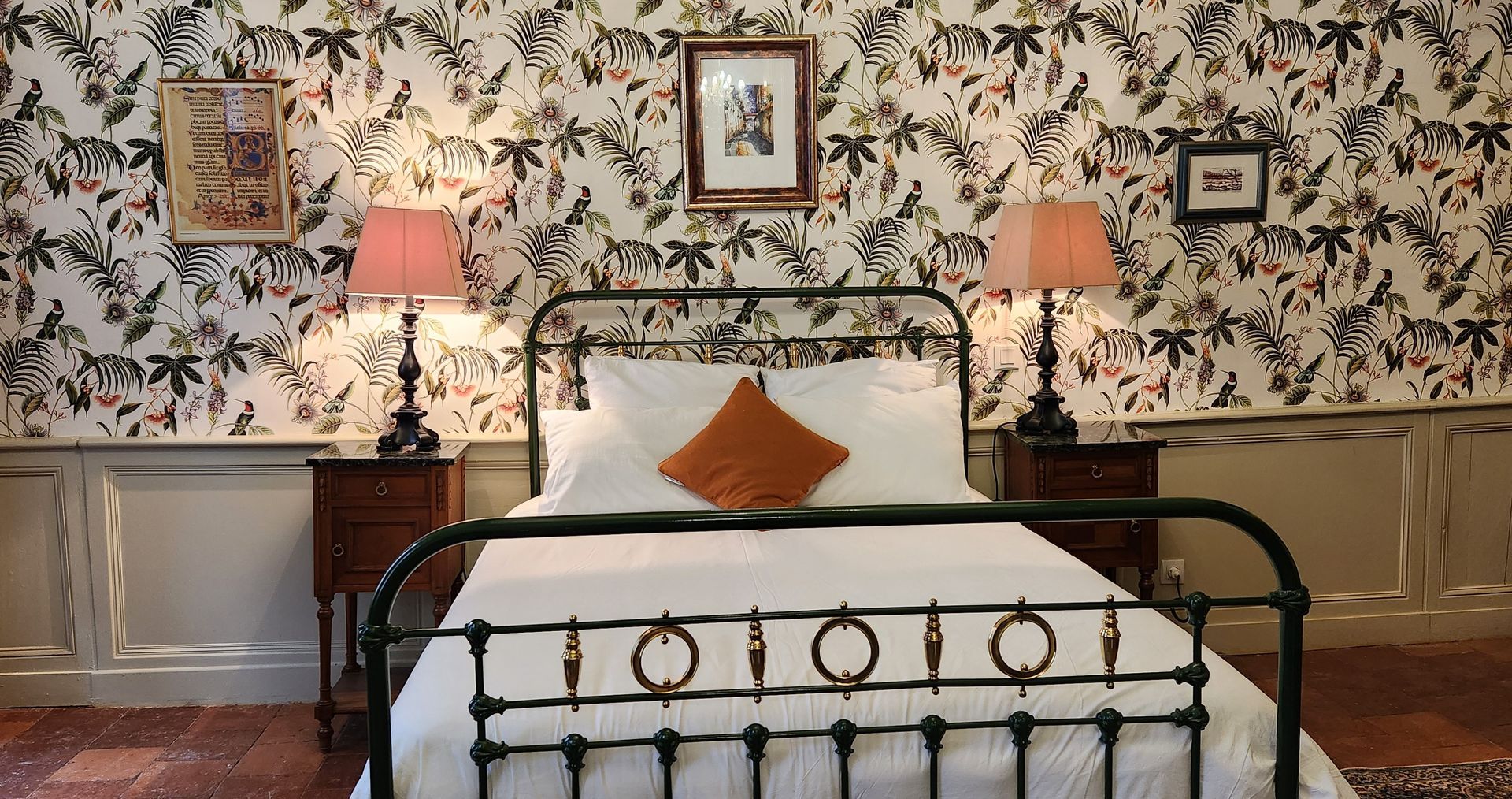 a bedroom with a bed , two lamps , and a floral wallpaper .