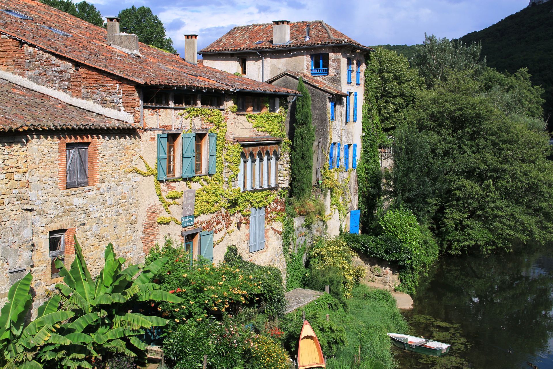 a row of buildings next to a river with a canoe in the water .