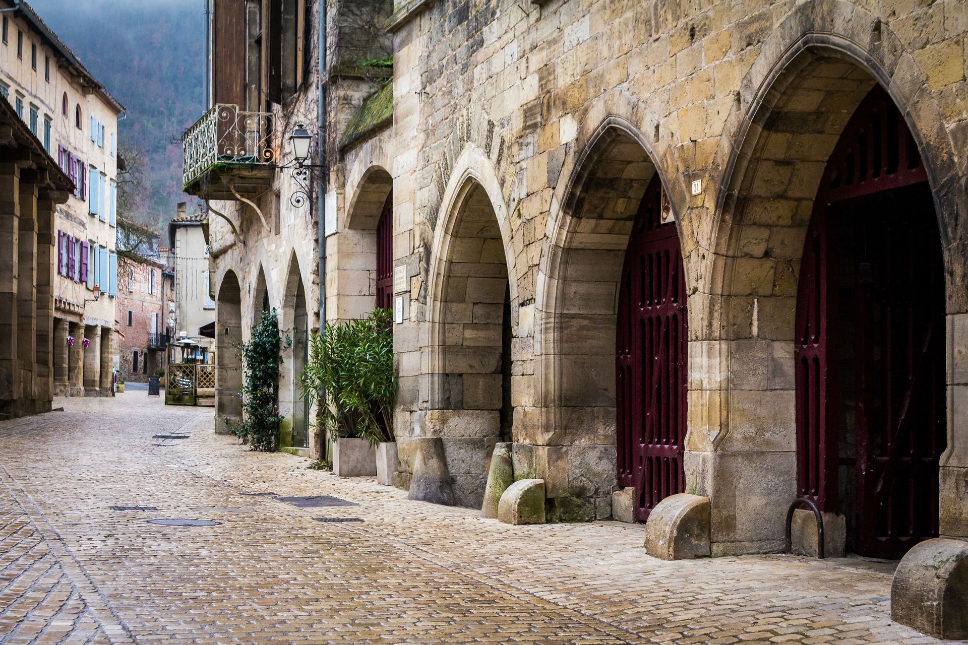 a cobblestone street with arches and buildings in a small town .