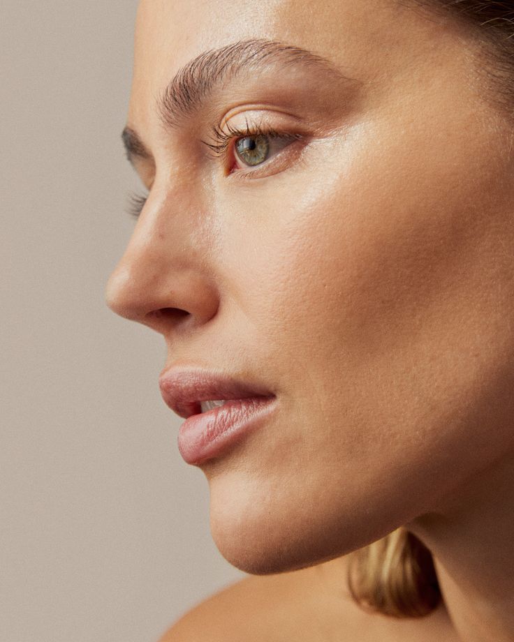 Woman's face in profile, with soft focus on skin; light skin tone, pale lips, open eyes.