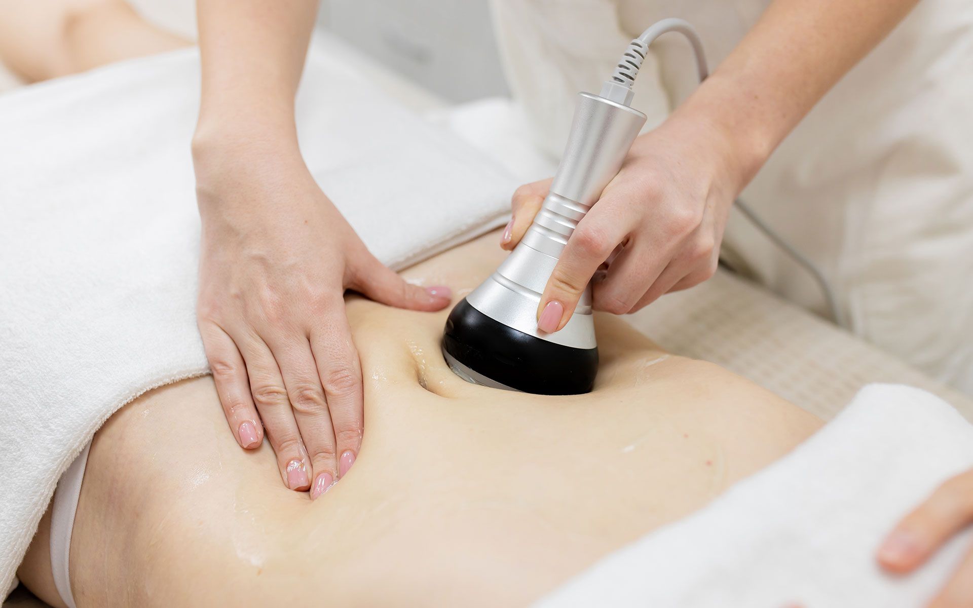 Person receiving abdomen treatment with handheld device; skin care procedure.