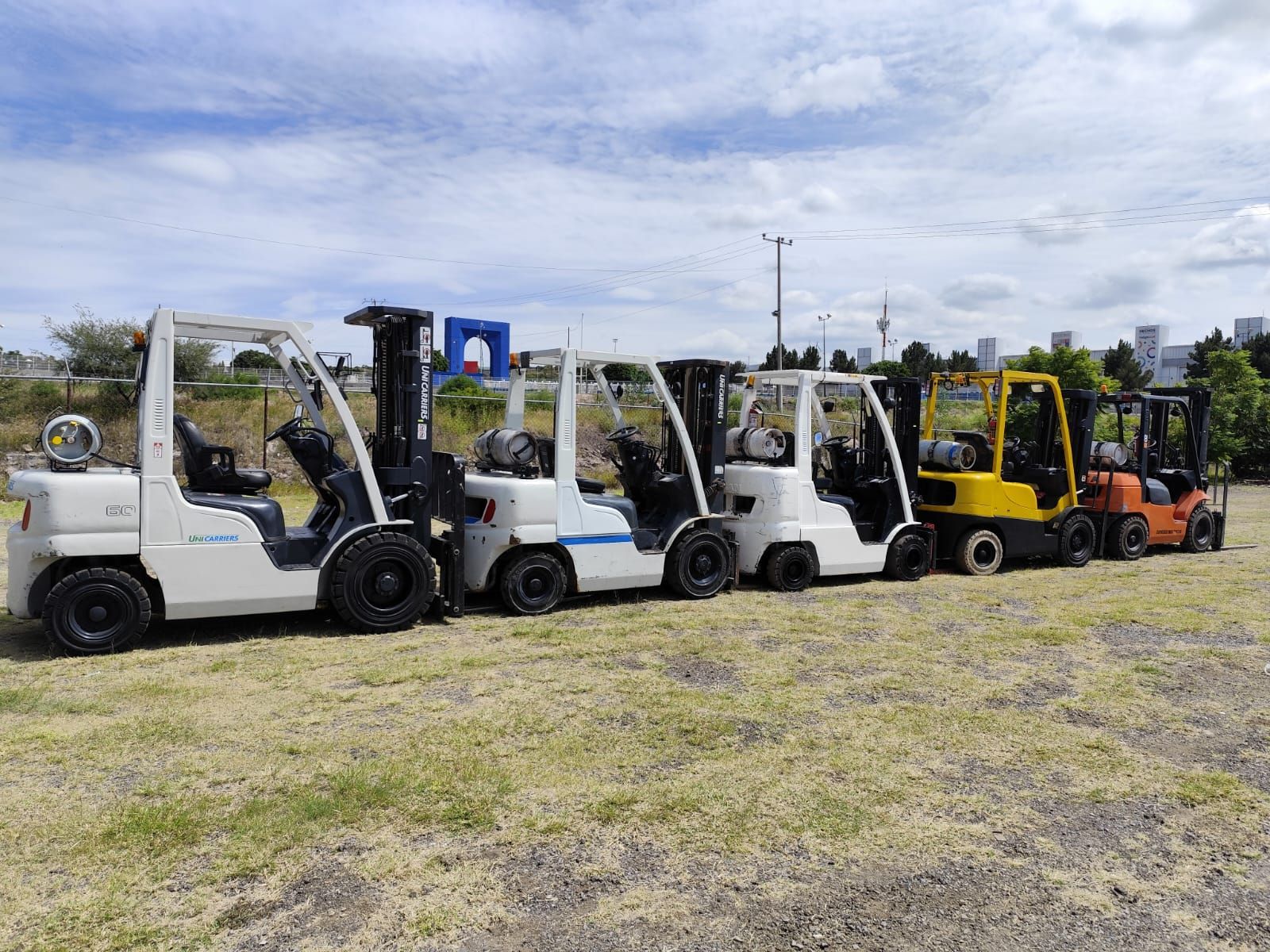 Una fila de carretillas elevadoras están estacionadas en un campo.
