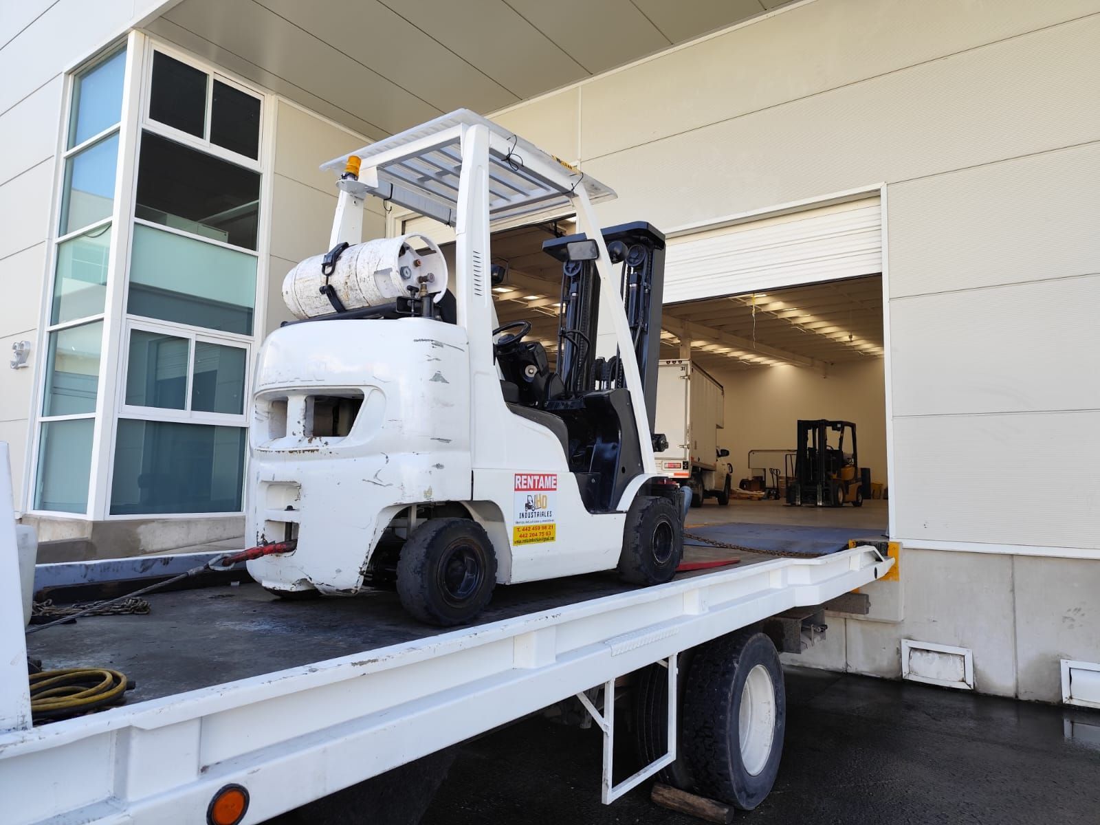 Una carretilla elevadora está sentada en la parte trasera de una grúa.
