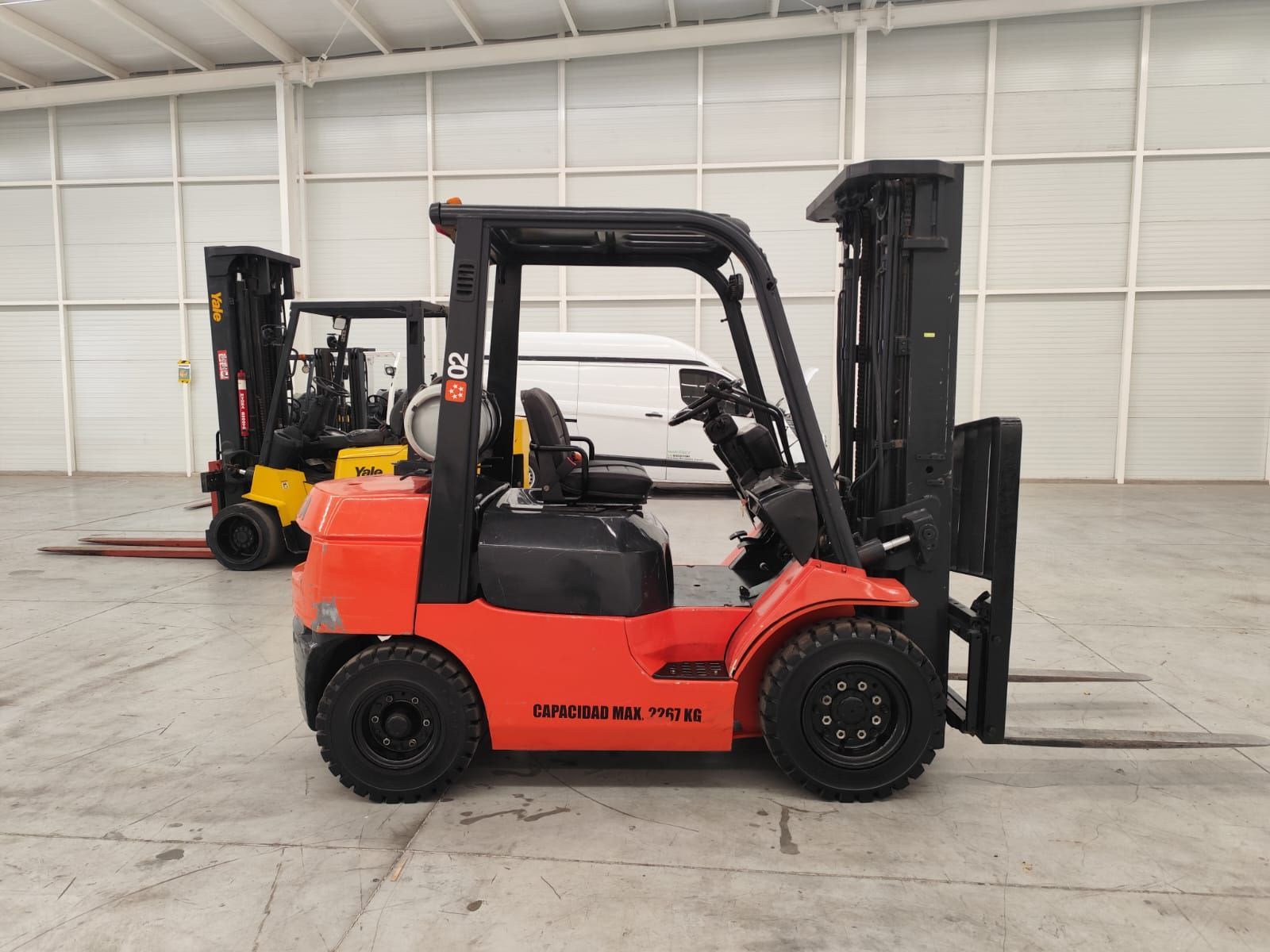 Una carretilla elevadora está estacionada en un almacén al lado de otra carretilla elevadora.