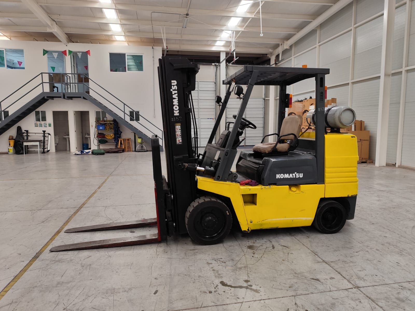 Una carretilla elevadora amarilla está estacionada en un gran almacén.