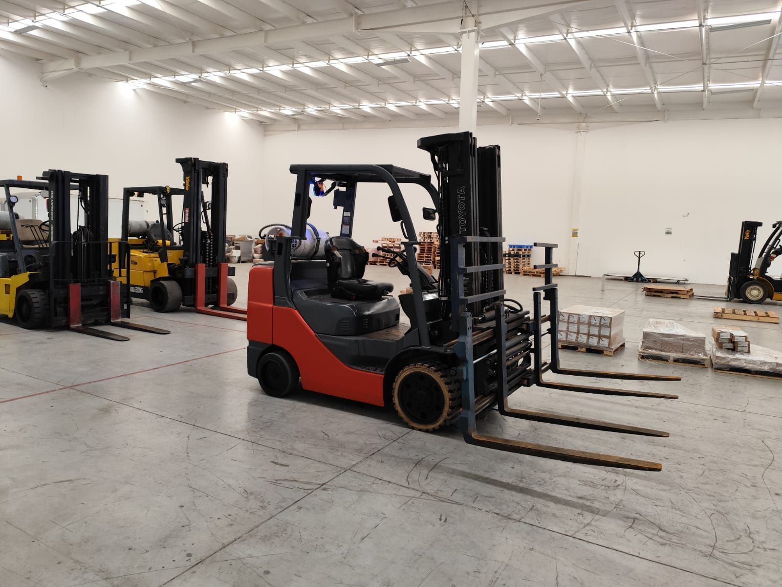 Una fila de carretillas elevadoras están estacionadas en un almacén.