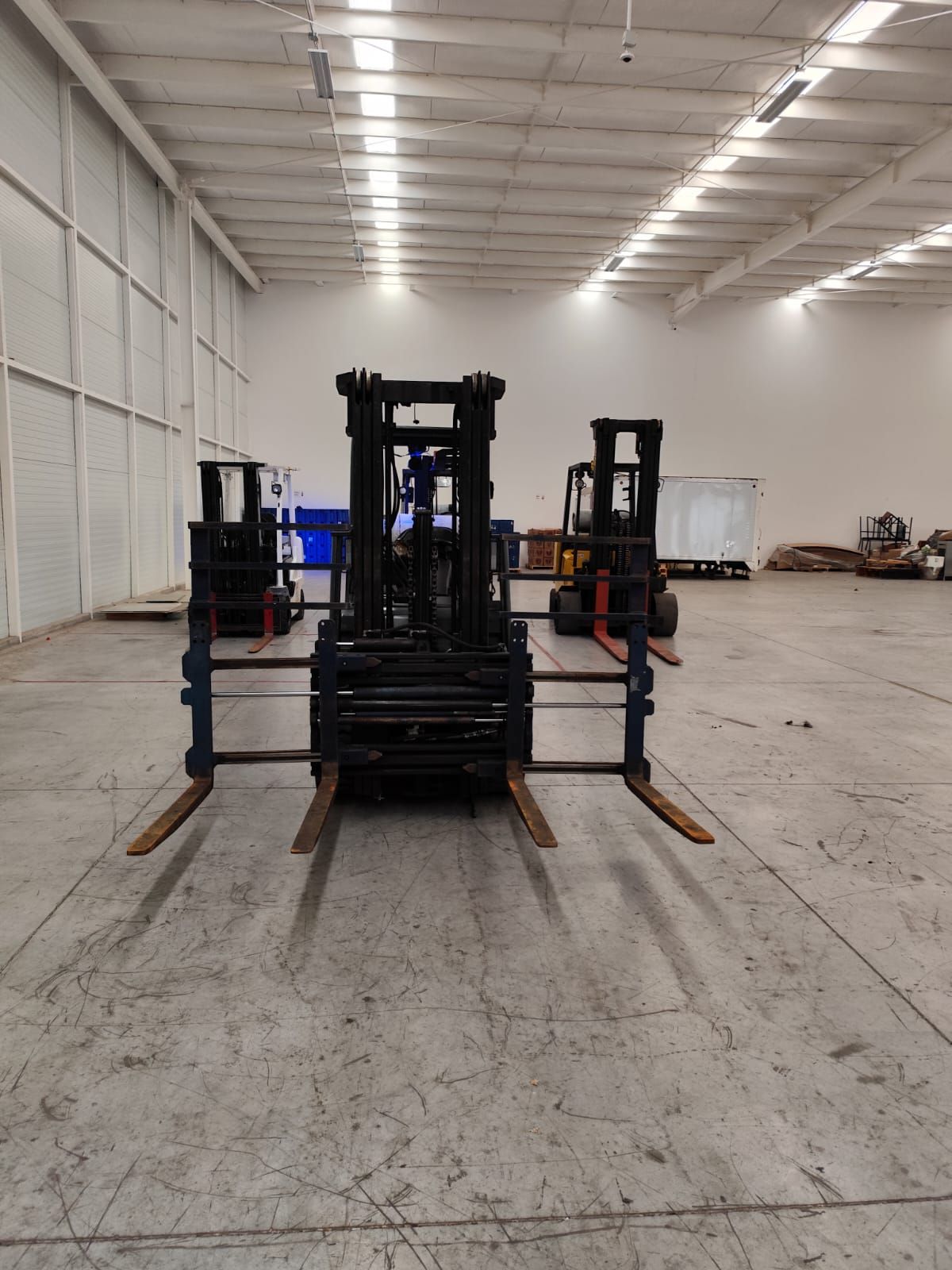 Dos carretillas elevadoras están estacionadas en un gran almacén.