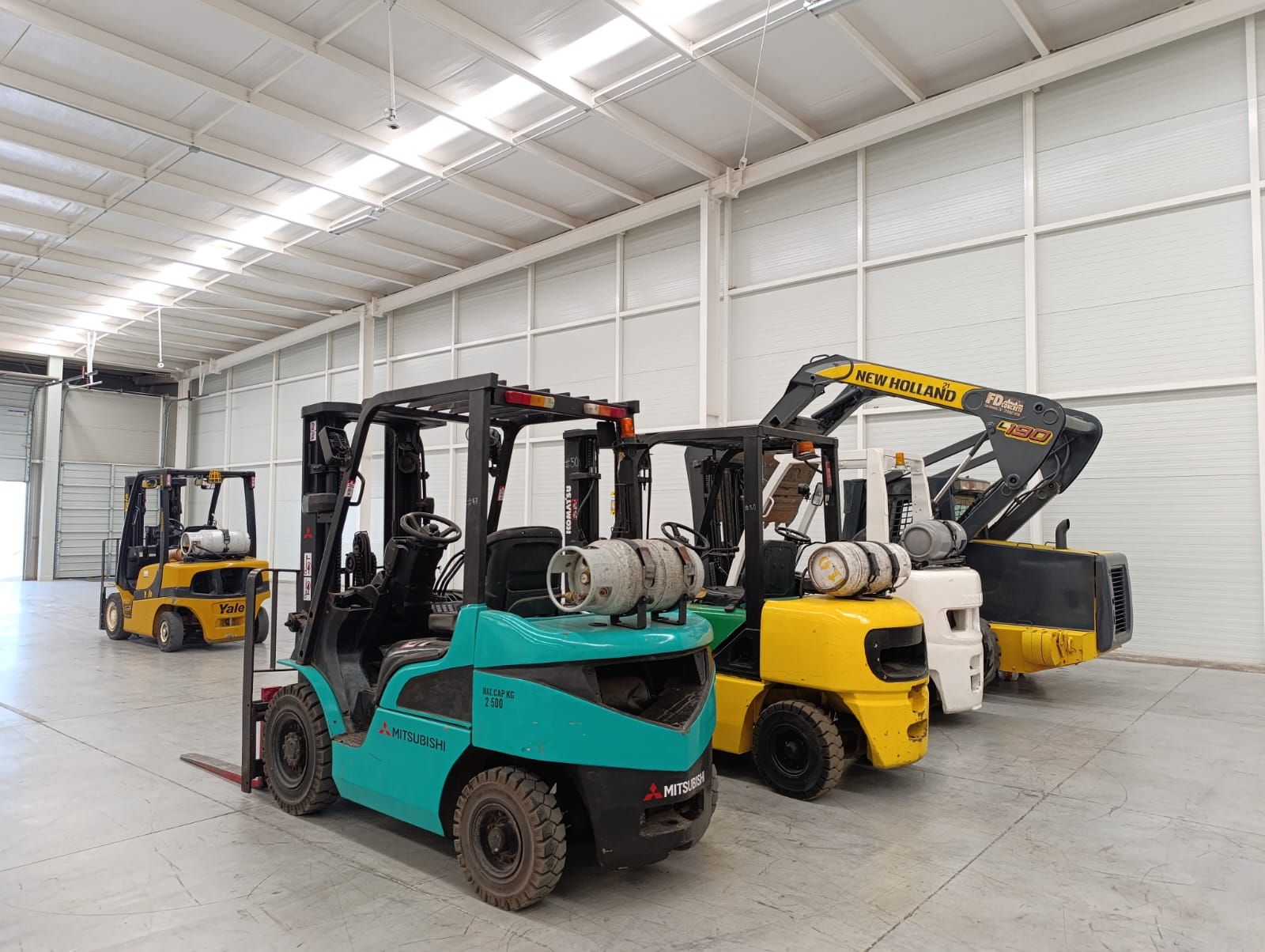 Una fila de carretillas elevadoras están estacionadas en un almacén.