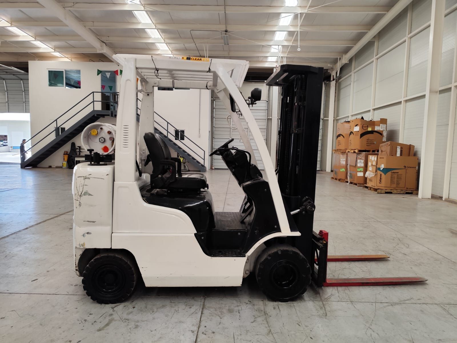 Una carretilla elevadora en blanco y negro está estacionada en un almacén.