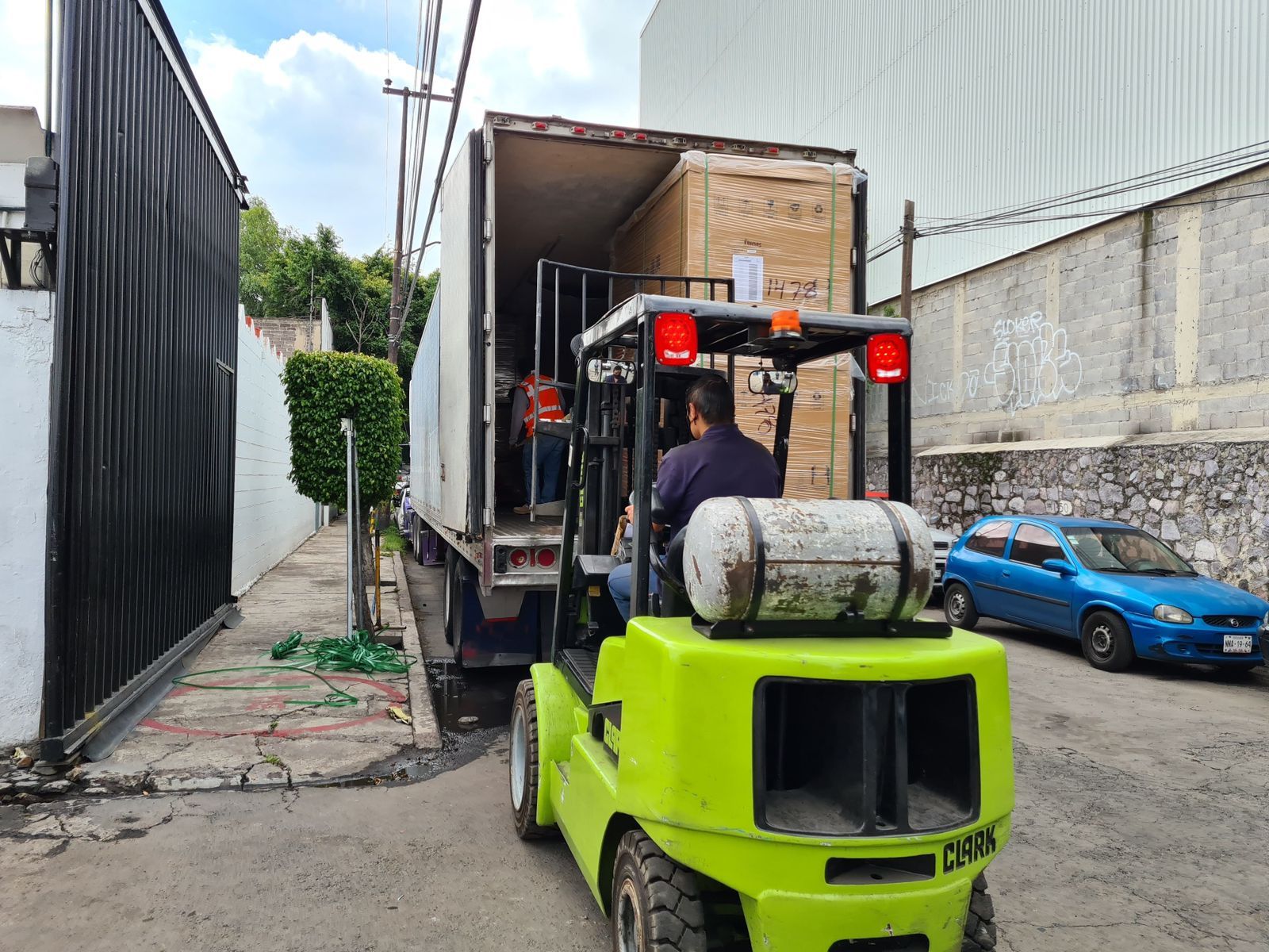 Un hombre conduce una carretilla elevadora en un estacionamiento.