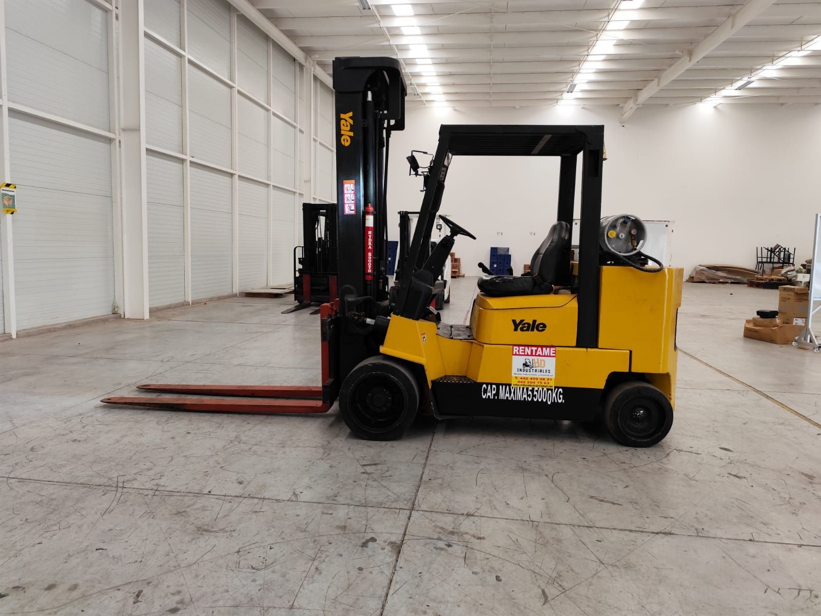 Una carretilla elevadora amarilla está estacionada en un gran almacén.