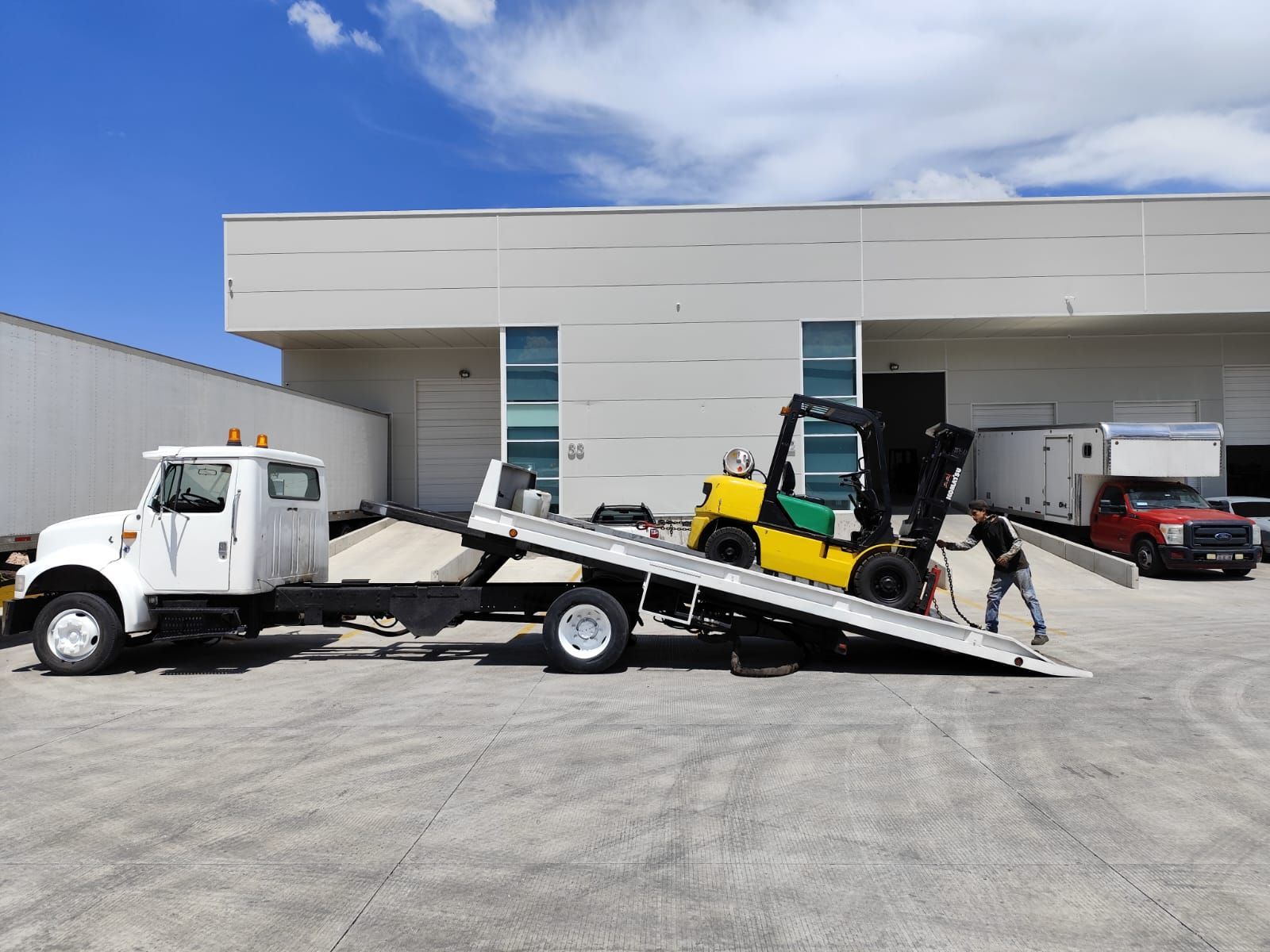 Una carretilla elevadora está siendo remolcada por una grúa en un estacionamiento.