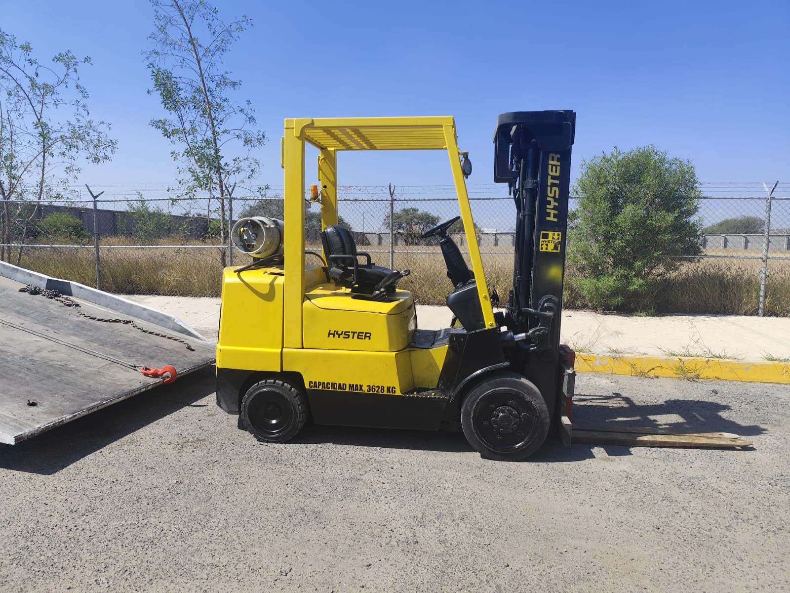 Una carretilla elevadora amarilla está estacionada al costado de la carretera.