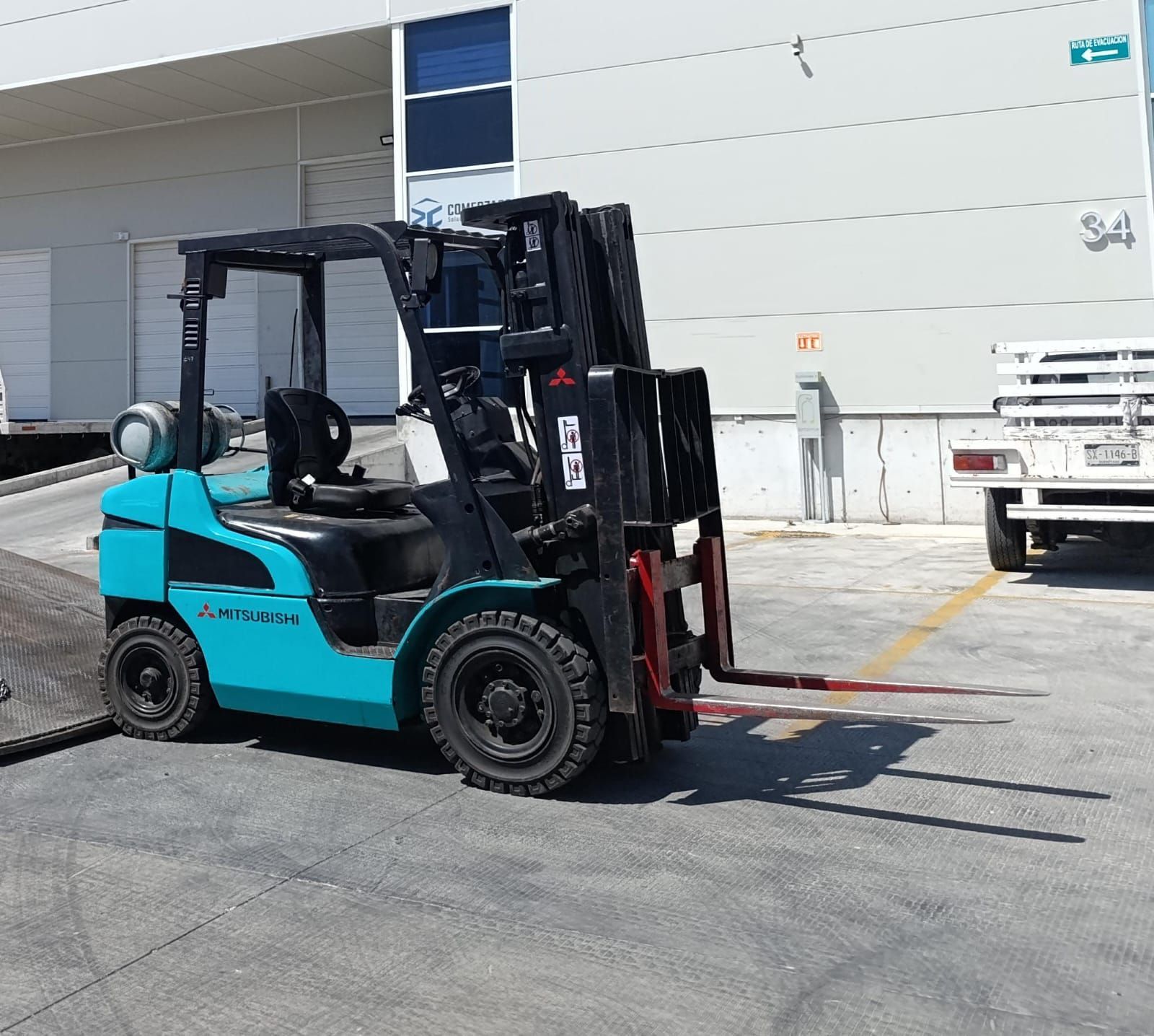 Una carretilla elevadora azul está estacionada frente a un edificio.