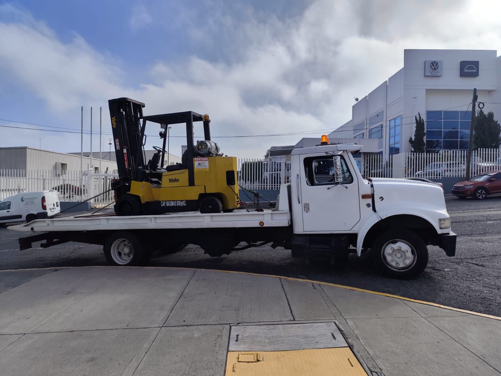 Una carretilla elevadora amarilla está en la parte trasera de una grúa.