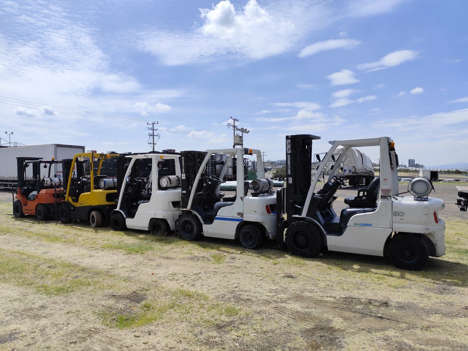 Una fila de carretillas elevadoras están estacionadas en un campo.