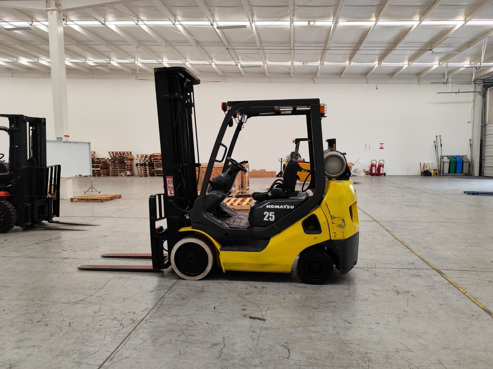 Una carretilla elevadora amarilla está estacionada en un almacén vacío.