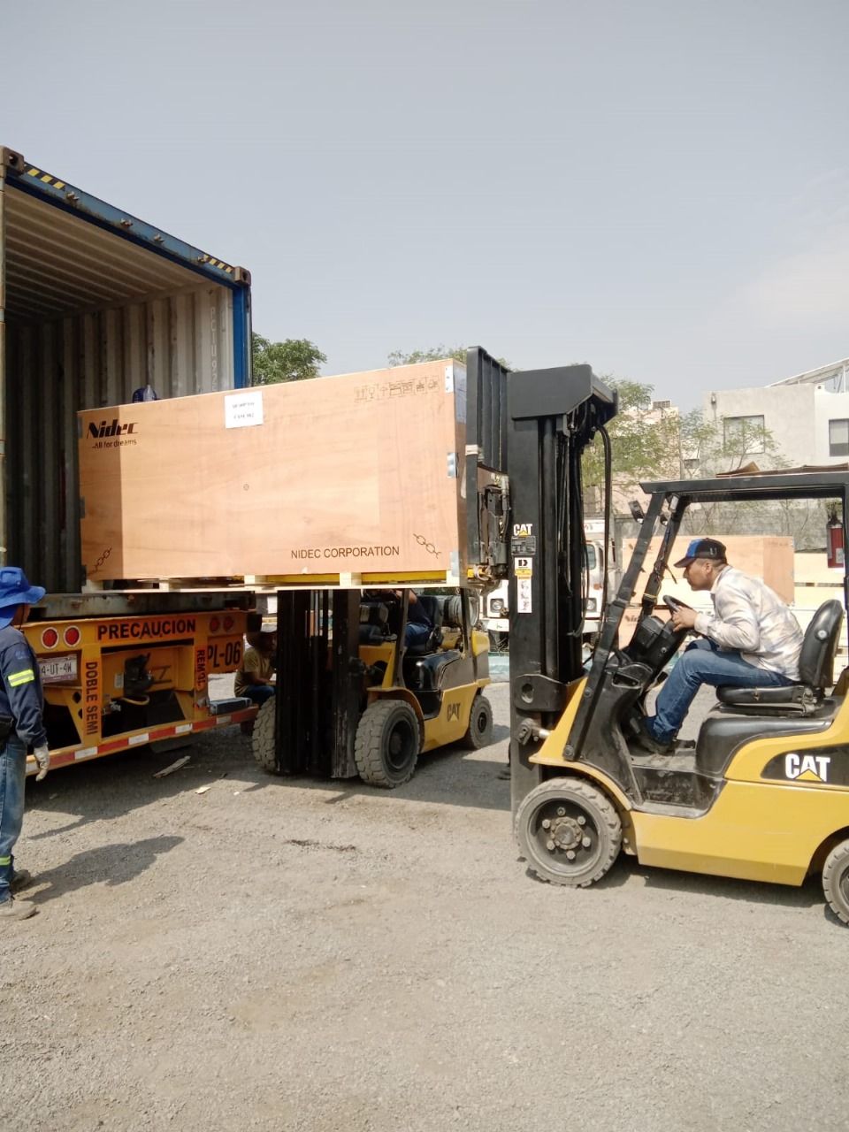 Un hombre conduce una carretilla elevadora que transporta una gran caja de madera.